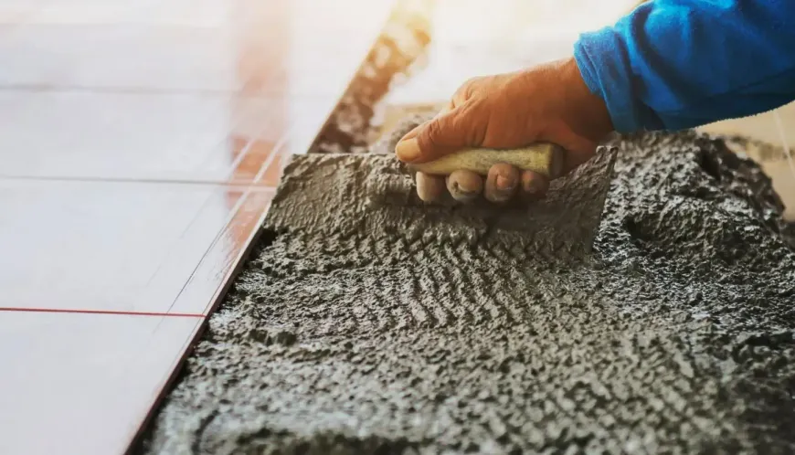 Person using a trowel to spread mortar for installing tile on a floor.