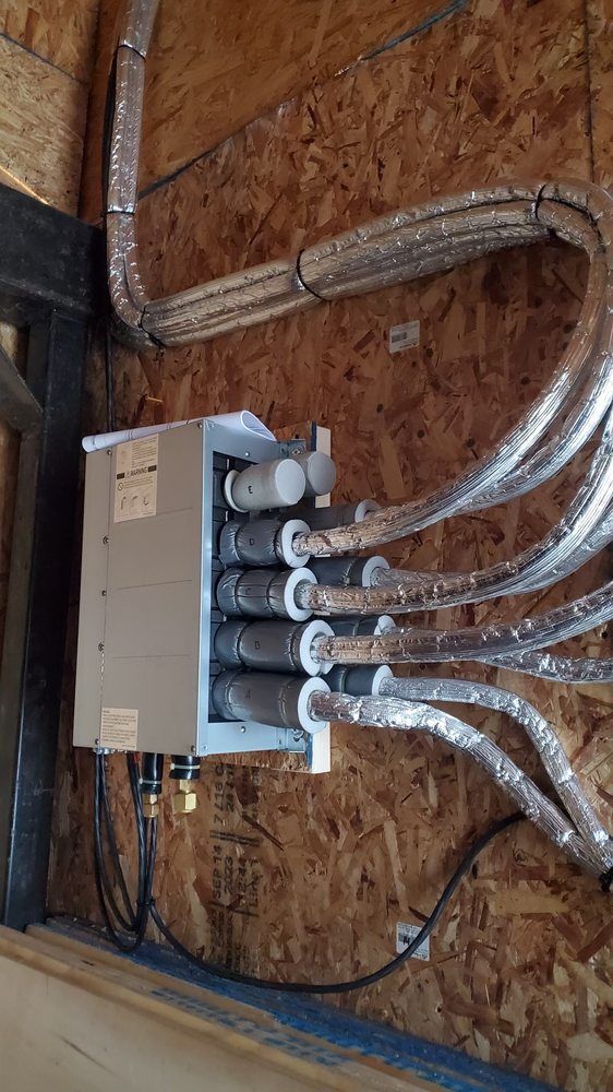 Box with pipes attached on a wood wall. Insulated silver tubes extend outwards.
