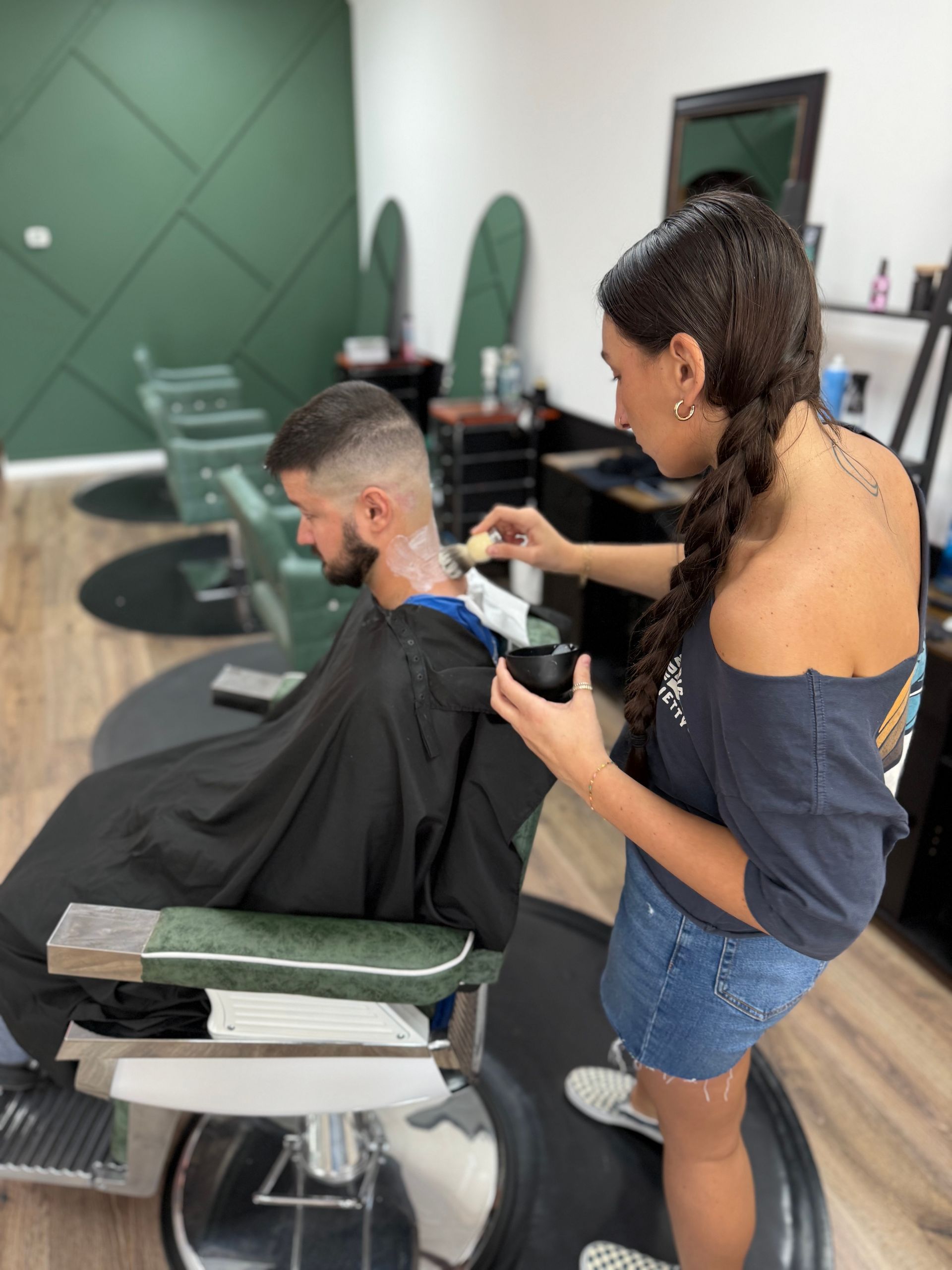 Barber applying product to a client's neck after a haircut in a salon.