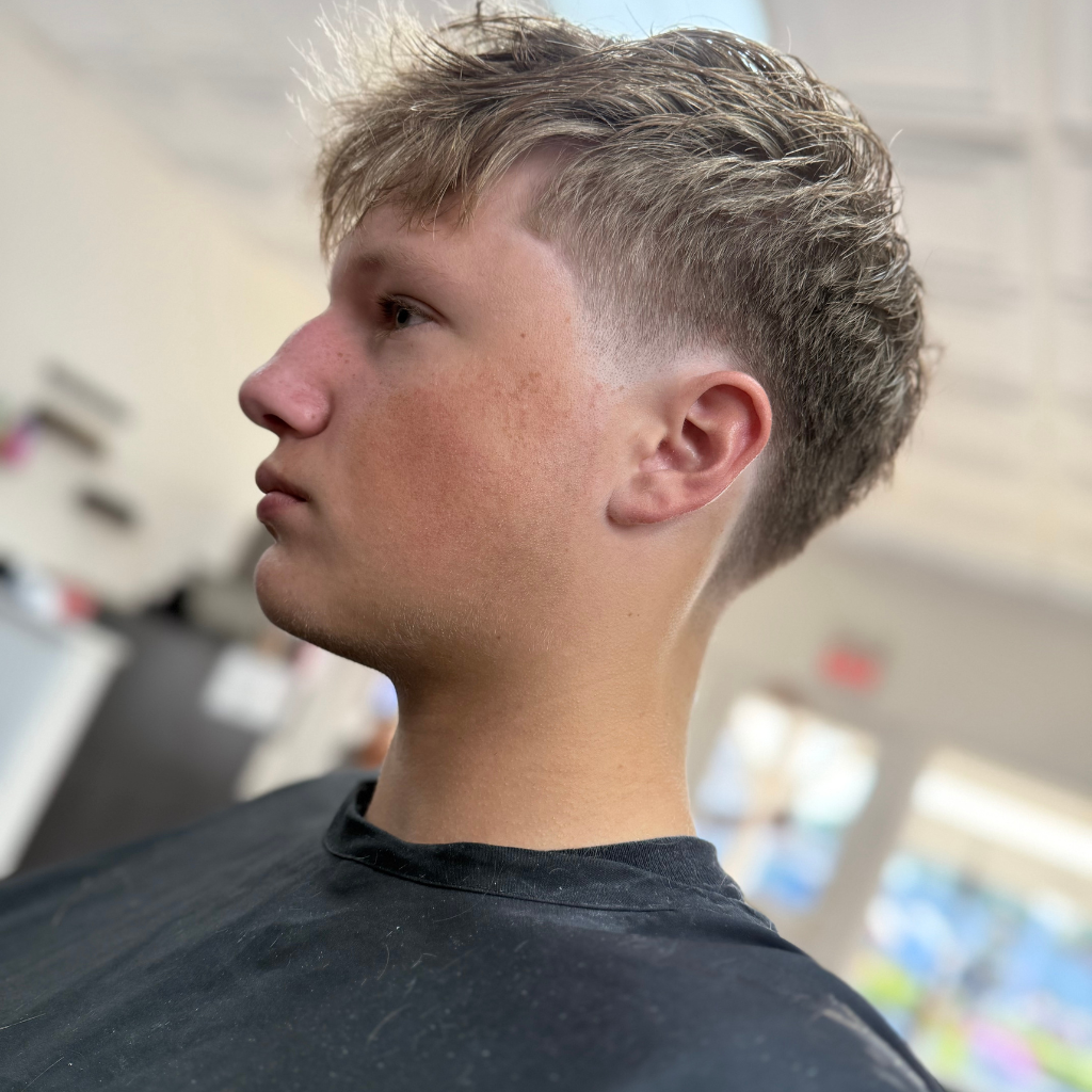 Person with a faded haircut, facing left in a salon setting.