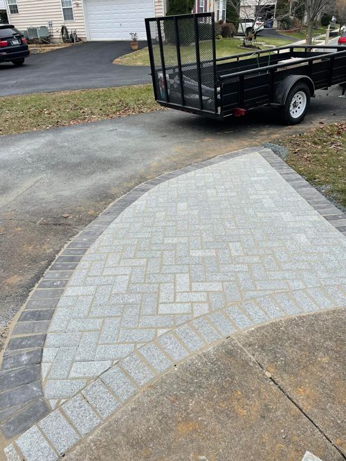A Trailer Is Parked In A Driveway Next To A Brick Walkway - Perry Hall, MD - Oakwood Landscaping LLC