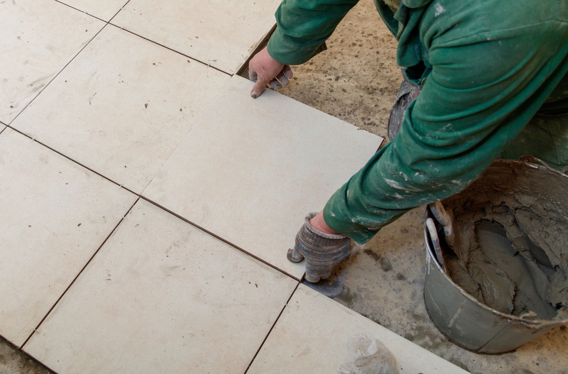 A man is laying tiles on a floor. A man is laying tiles on a floor.