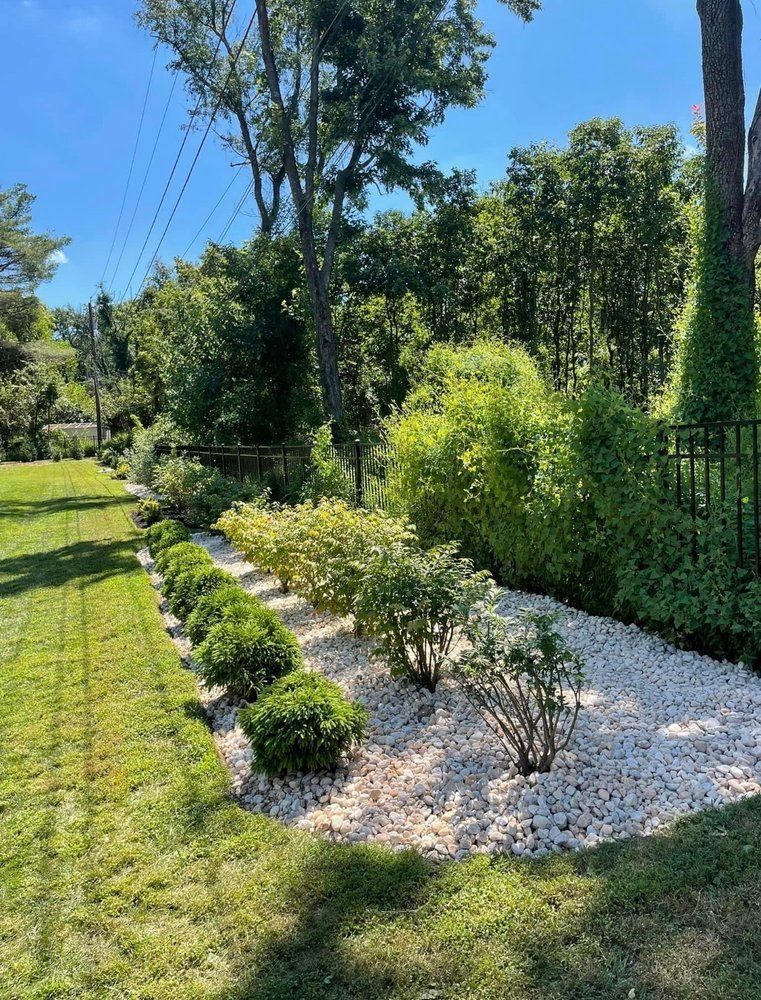 A Lush Green Garden Filled With Lots Of Plants And Rocks On A Sunny Day - Perry Hall, MD - Oakwood Landscaping LLC