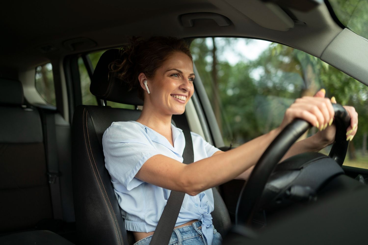 A woman is driving a car and looking at the rear view mirror