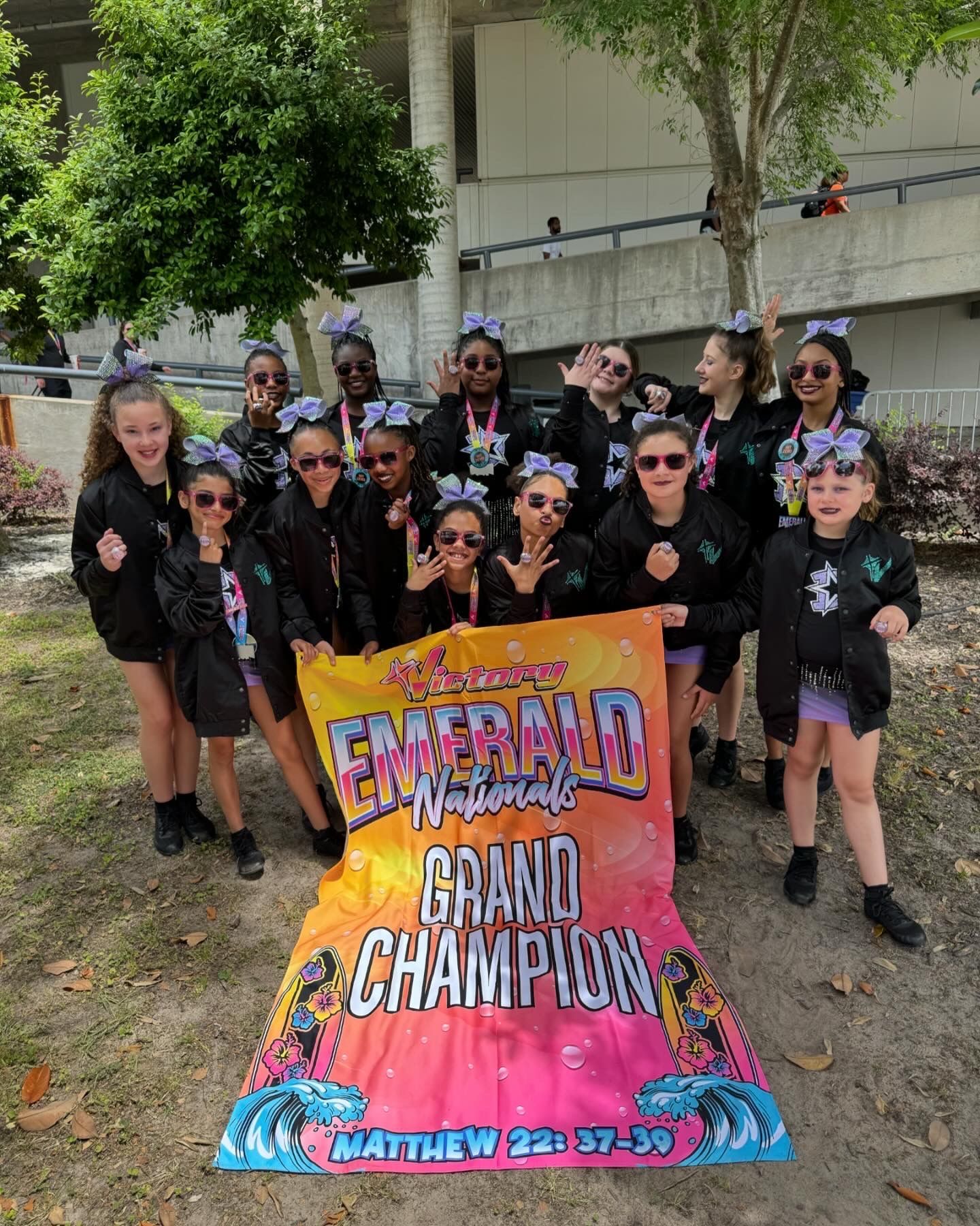 A group of young girls are posing for a picture with a banner that says `` grand champion ''.