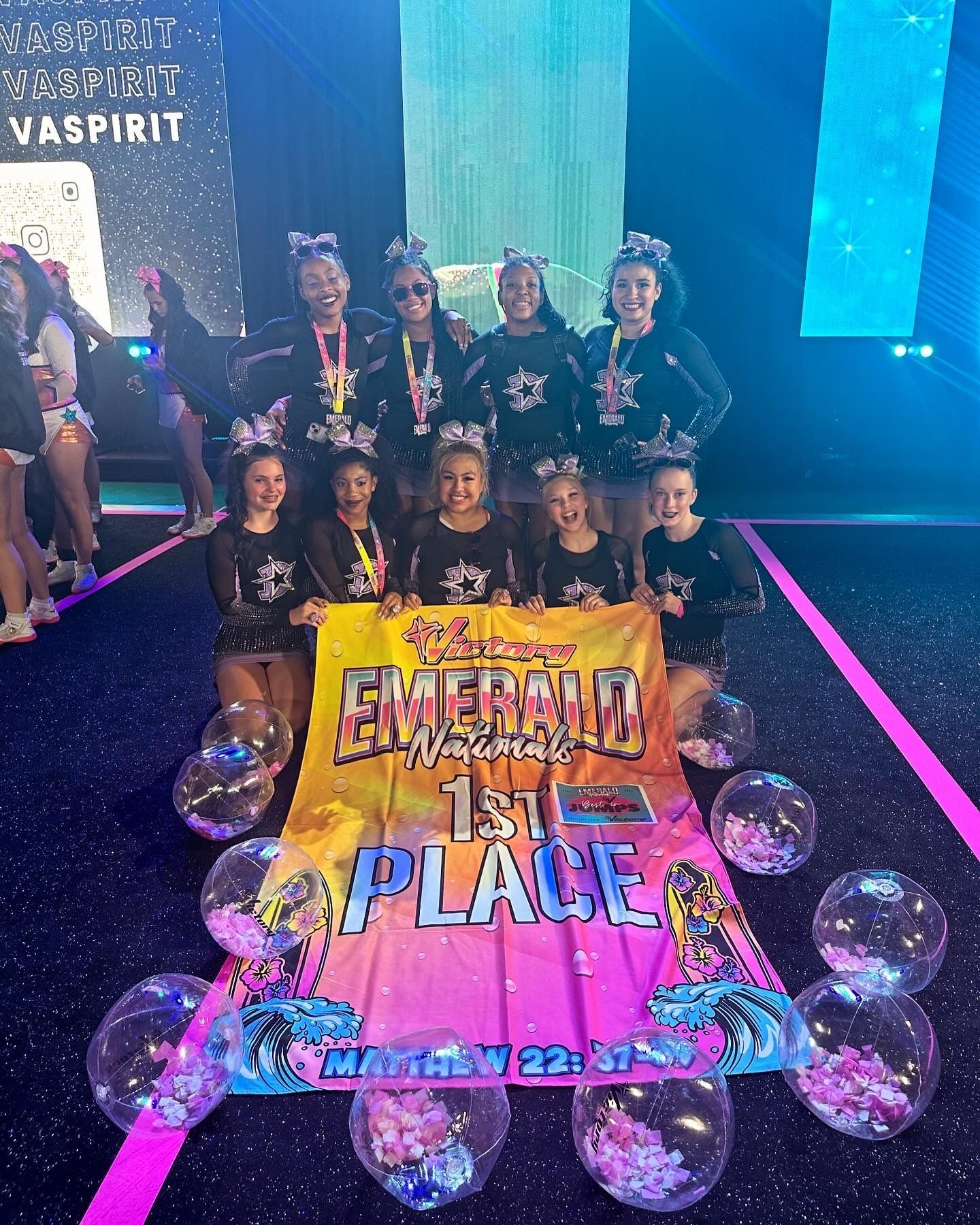 A group of cheerleaders are posing for a picture on a stage.