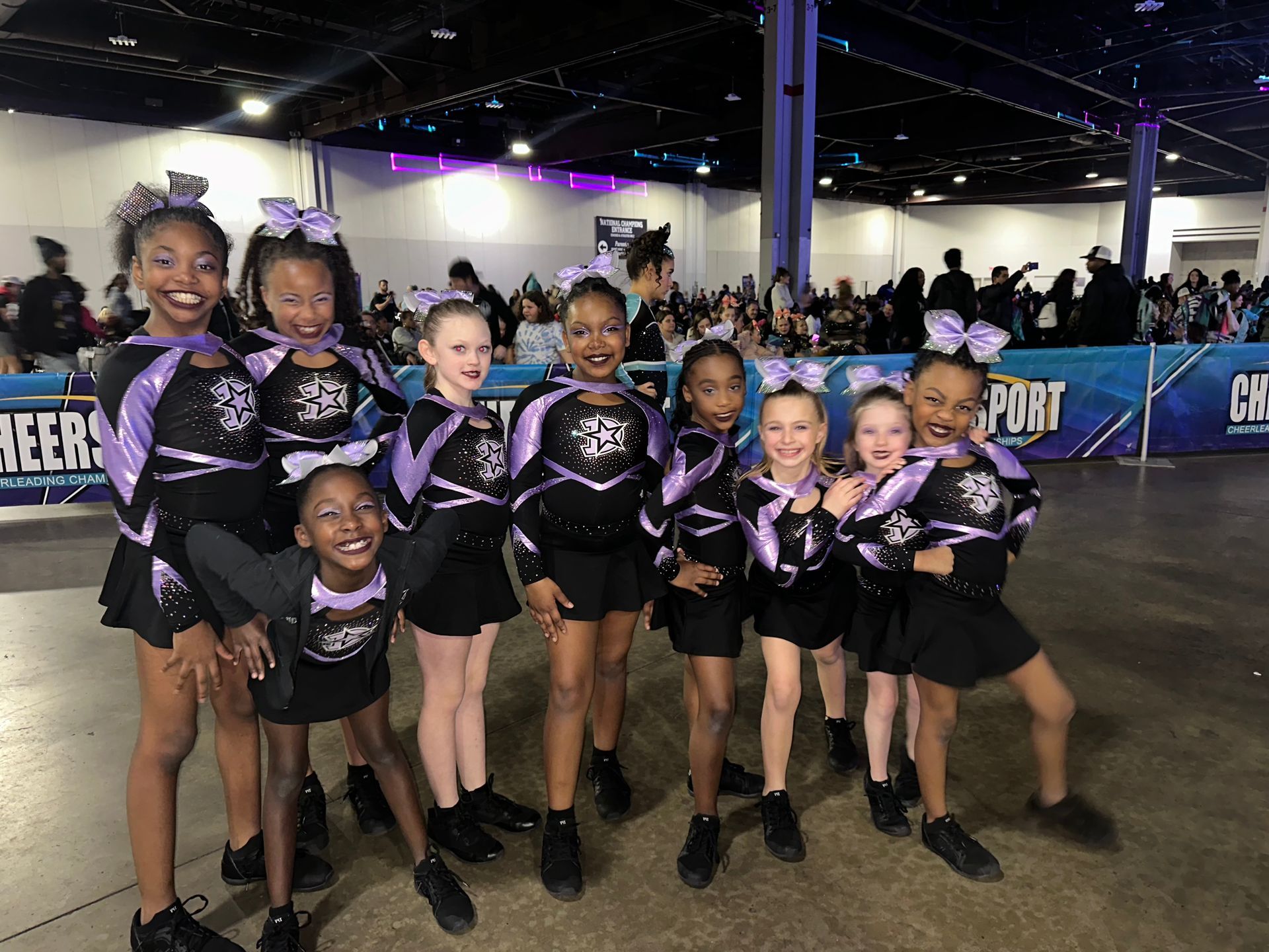 A group of cheerleaders are posing for a picture in a room.