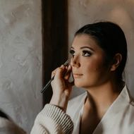 A woman is applying makeup to her face with a brush.