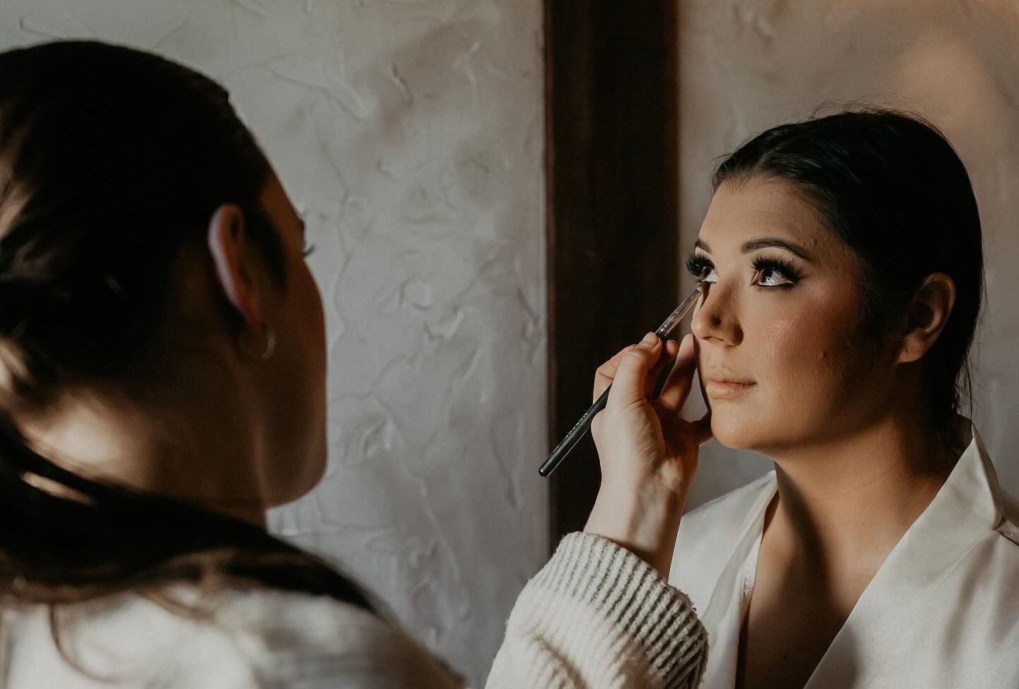 A woman is applying makeup to another woman 's face.