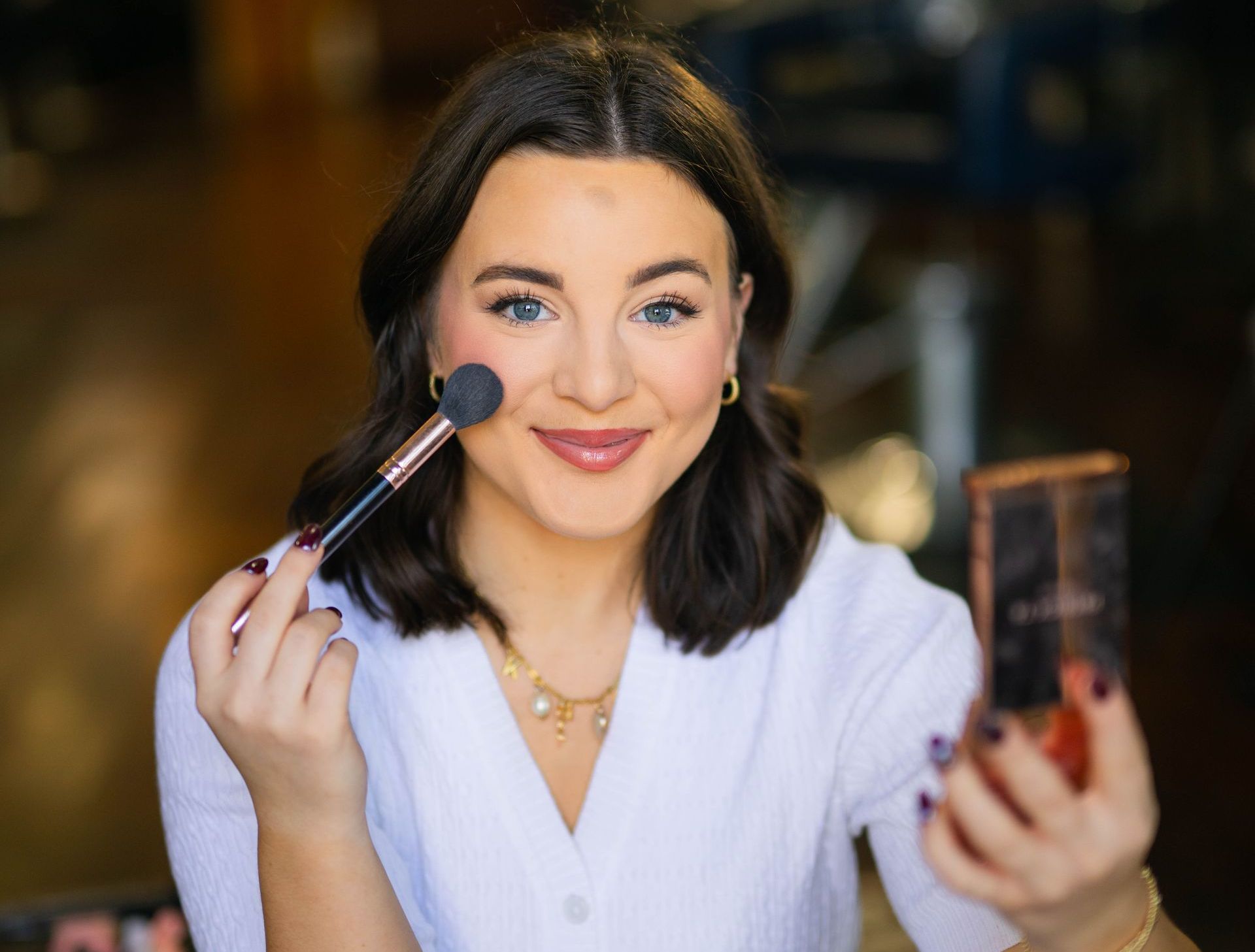 A woman is applying makeup to her face with a brush.