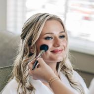 A woman is getting her makeup done by a makeup artist