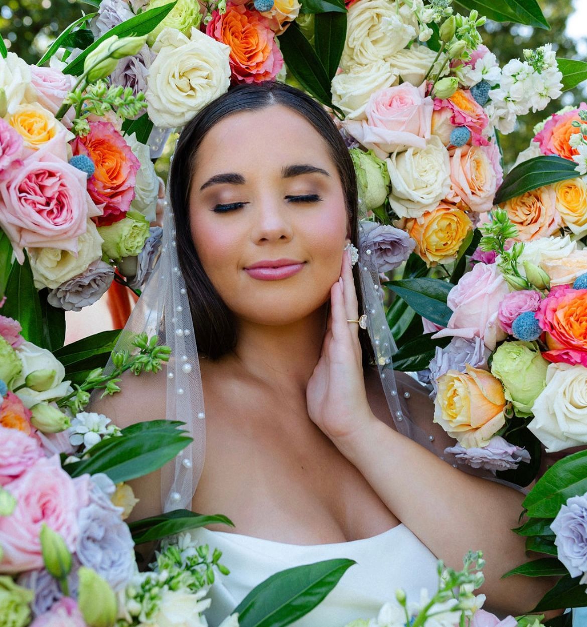 A woman in a white dress is surrounded by flowers