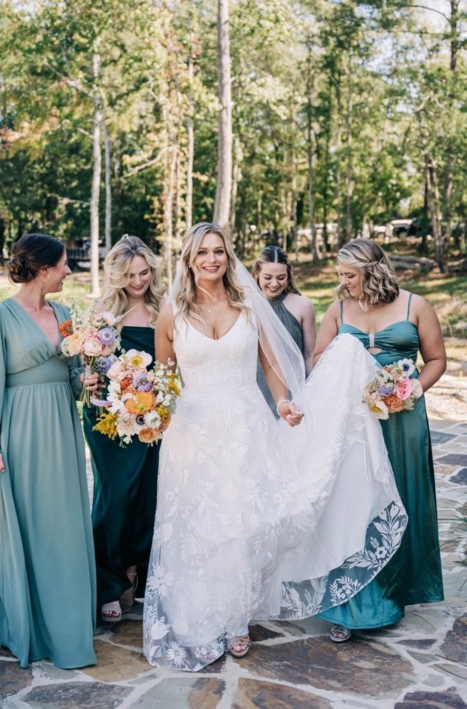 A bride and her bridesmaids are standing next to each other on a stone walkway.