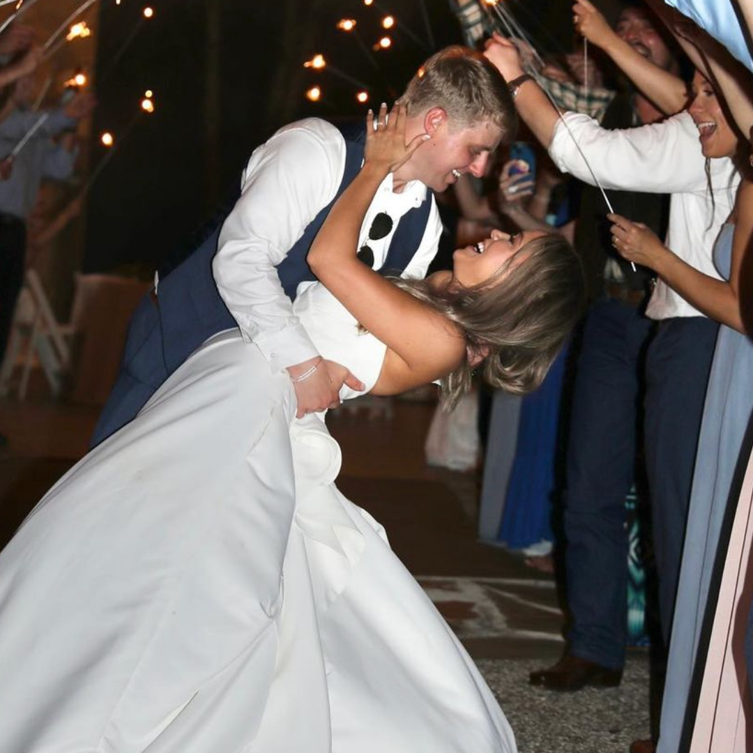 A bride and groom kissing in front of their wedding guests