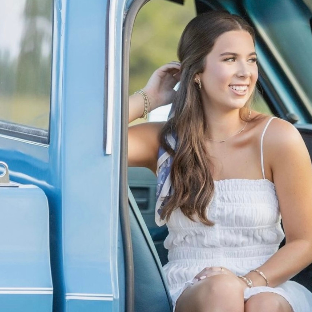 A woman in a white dress is sitting in a blue truck
