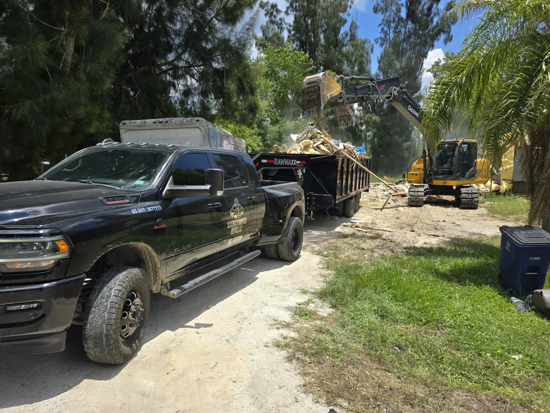 A black truck is parked on the side of a dirt road.