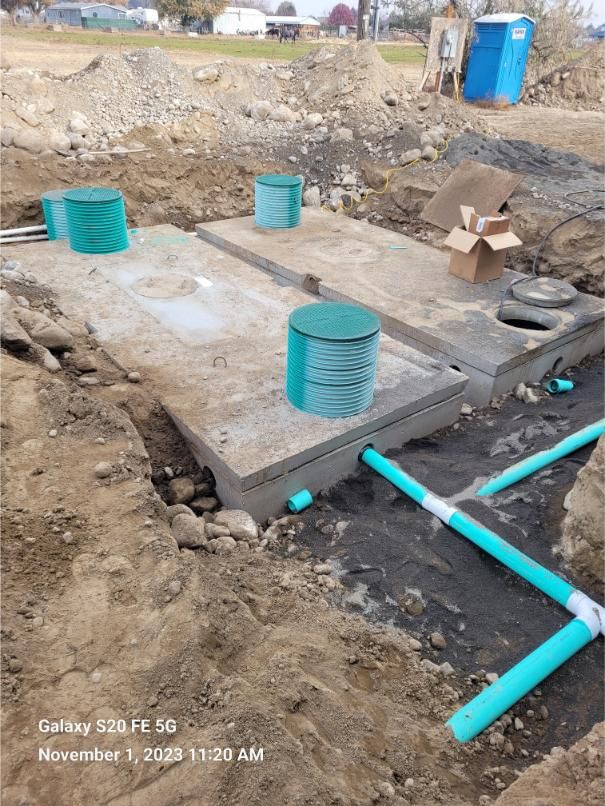A septic tank is being built in a dirt field.