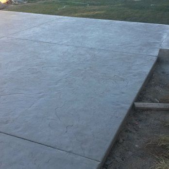 A concrete patio with a grassy area in the background.