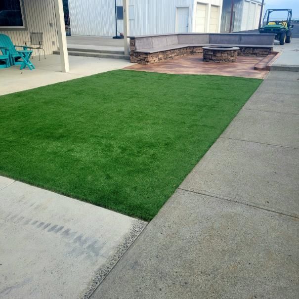 A large lawn with a bench and chairs in the background