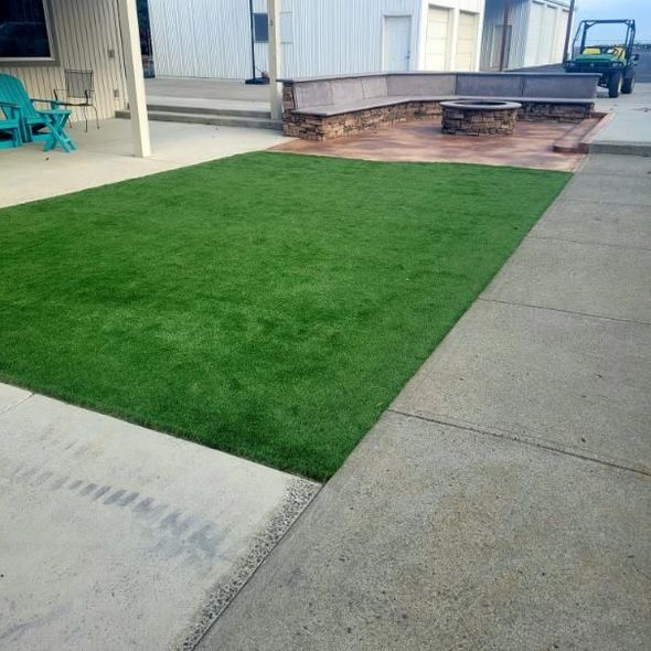 A large lawn with a bench and chairs in the background
