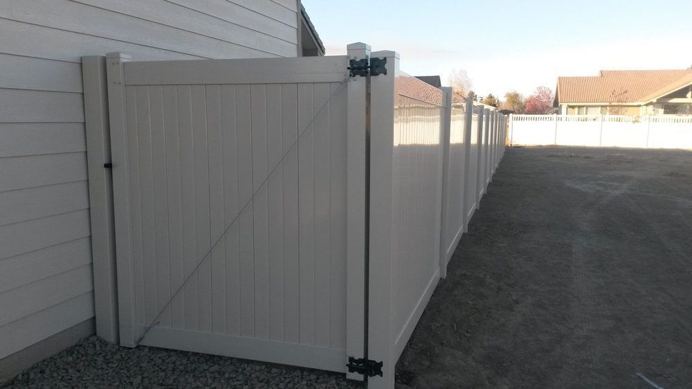A white fence with a gate in front of a house.