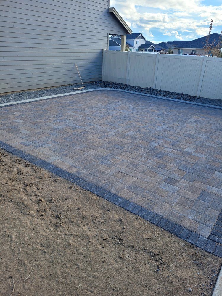 A brick driveway is being built in front of a house.