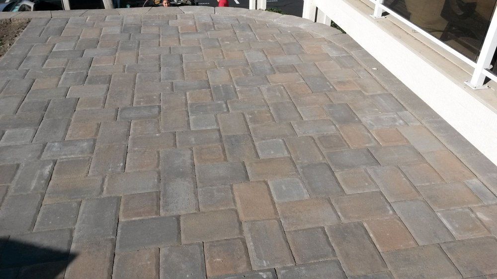 A brick walkway with a white railing in the background