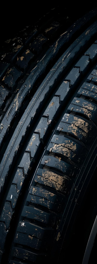Close-up of a black tire with worn tread, covered in dirt.
