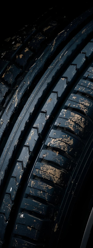 Close-up of a black tire with worn tread, covered in dirt.