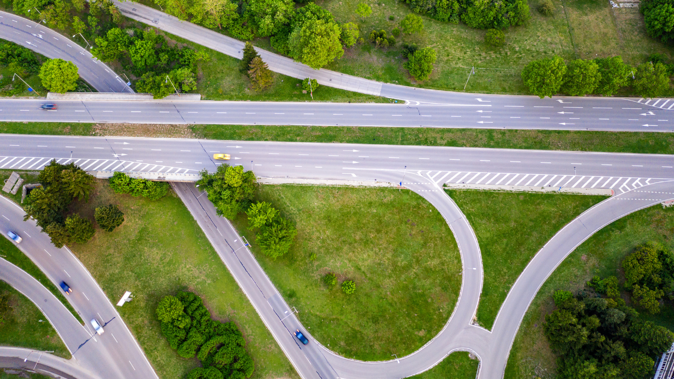 An aerial view of a highway intersection surrounded by trees and grass.