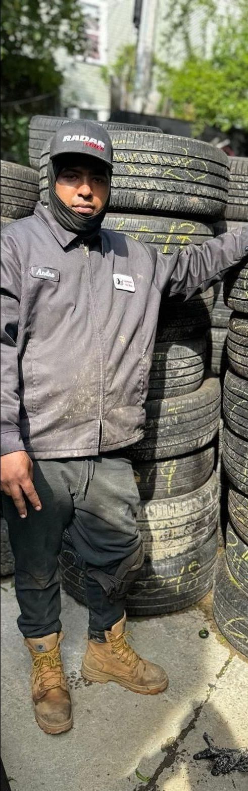 A man is standing in front of a pile of tires.