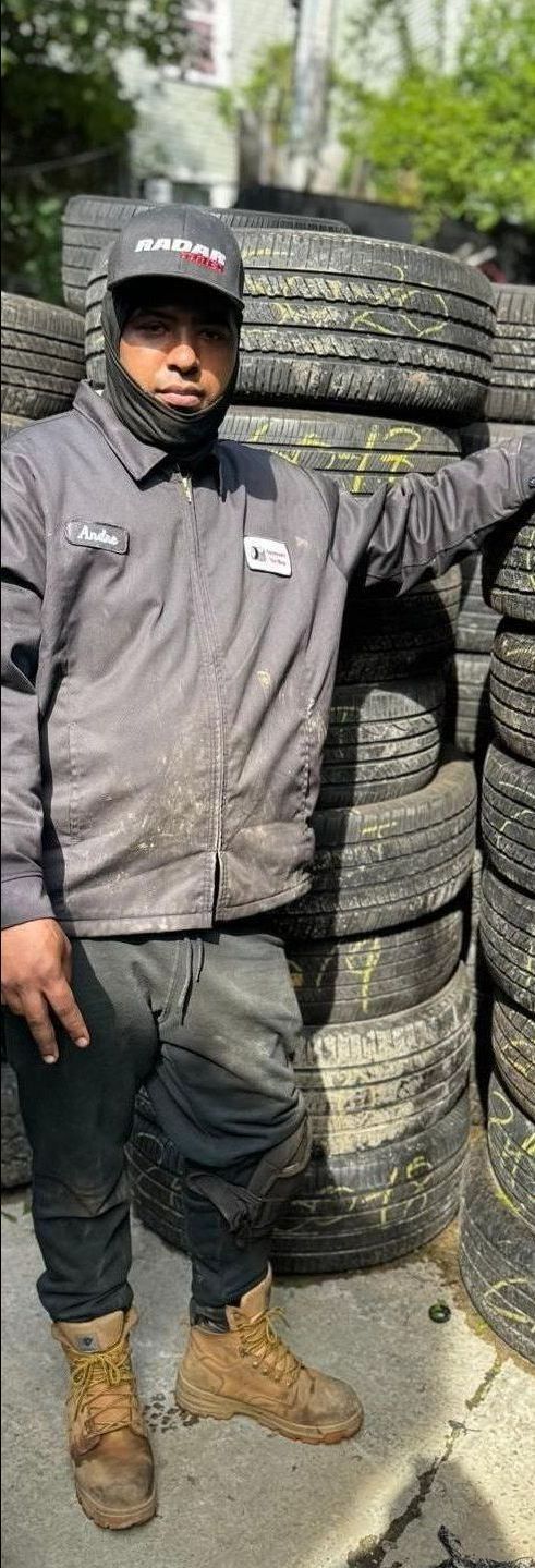 A man is standing in front of a pile of tires.
