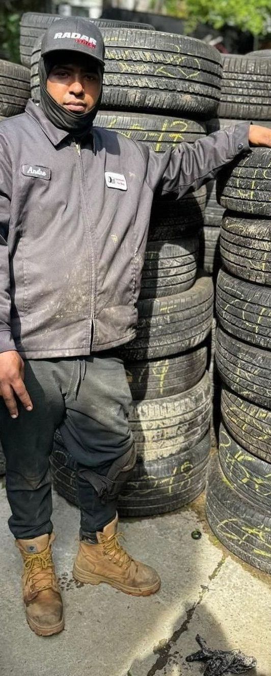 A man is standing in front of a pile of tires.