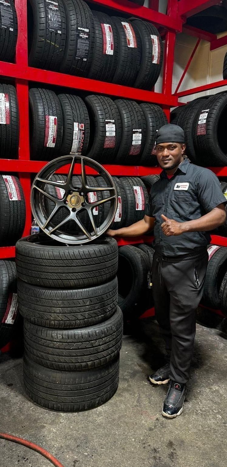 A man is standing next to a pile of tires in a tire shop.