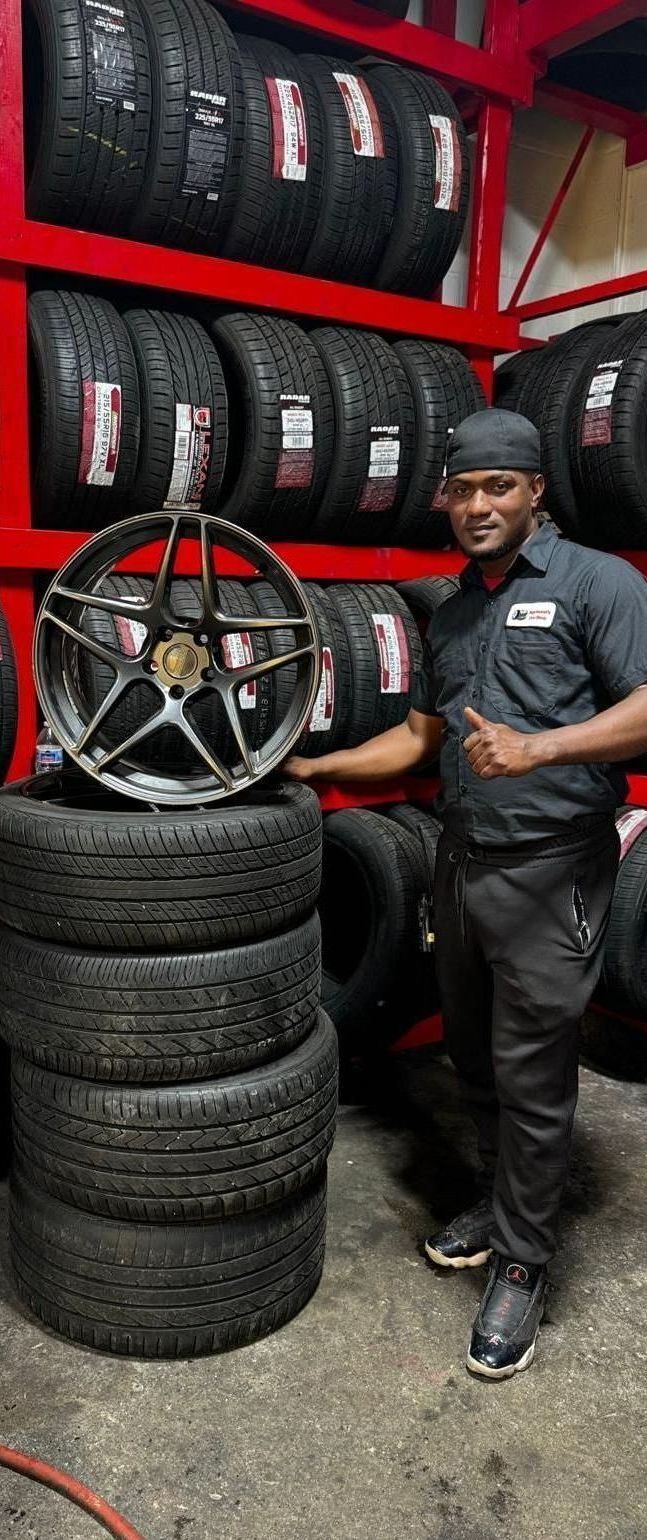 A man is standing next to a pile of tires in a tire shop.