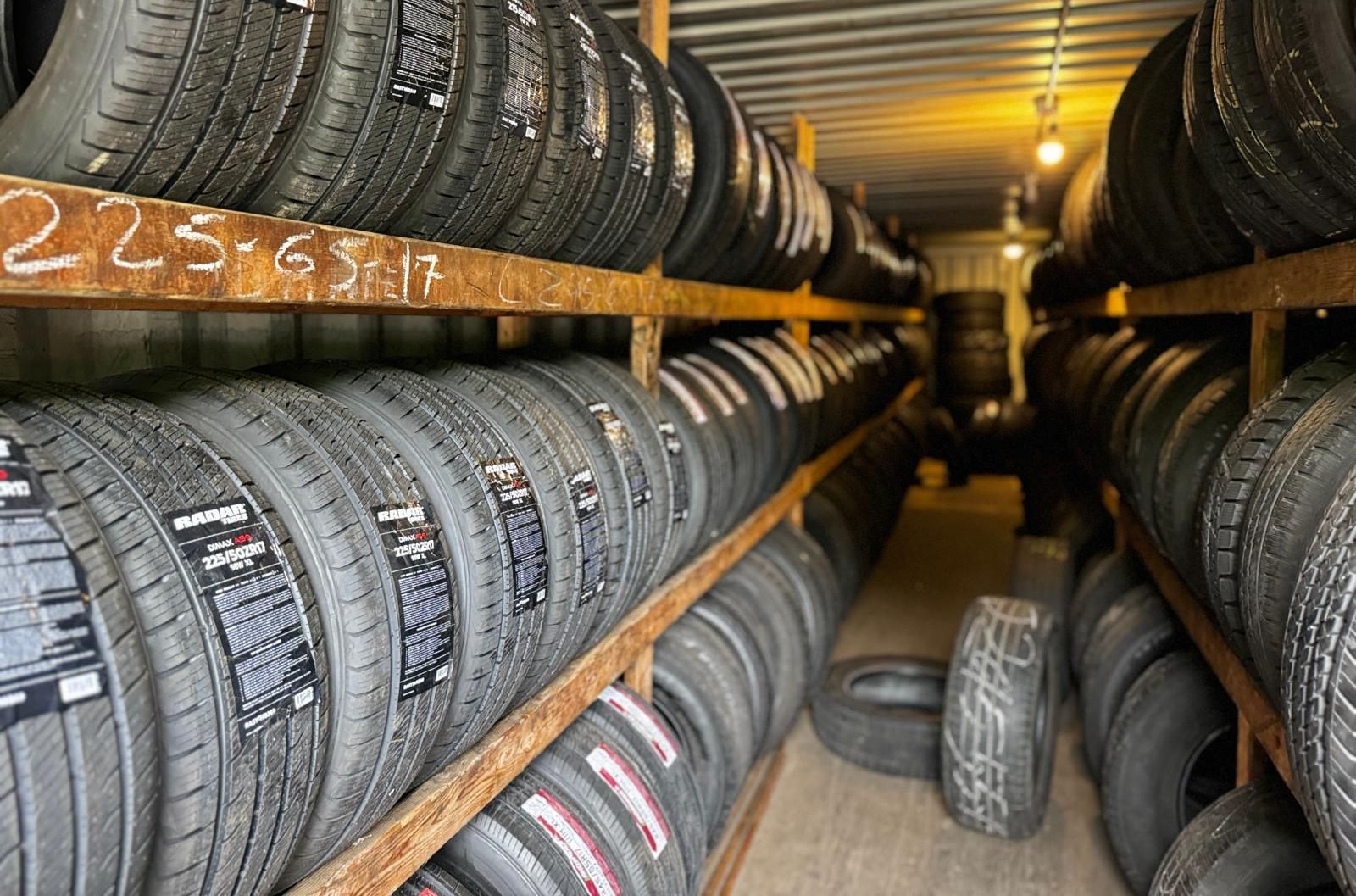 A bunch of tires are stacked on shelves in a garage
