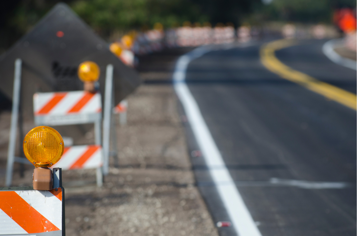 Road construction site with barricades and warning lights on a curved road.