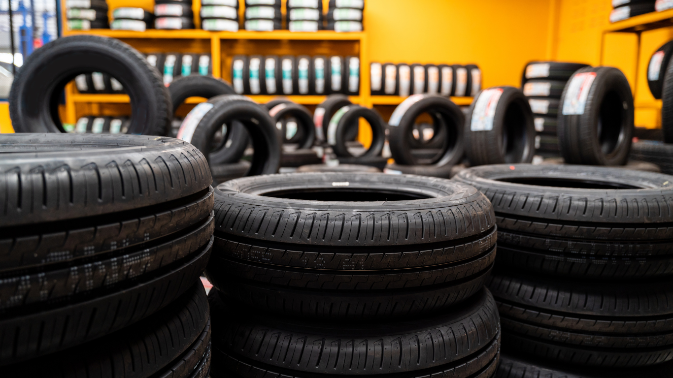 Tires stacked in the foreground with many more tires in the background, in an auto shop.