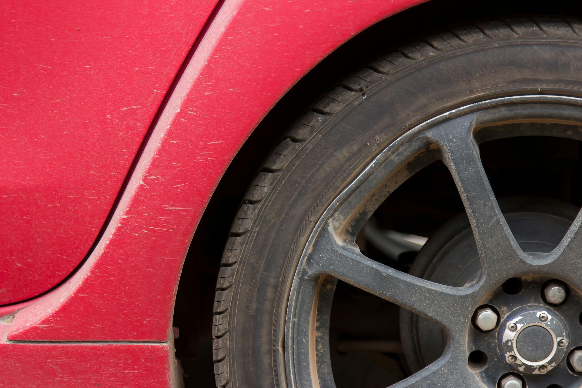 A close up of a red car 's tire and wheel