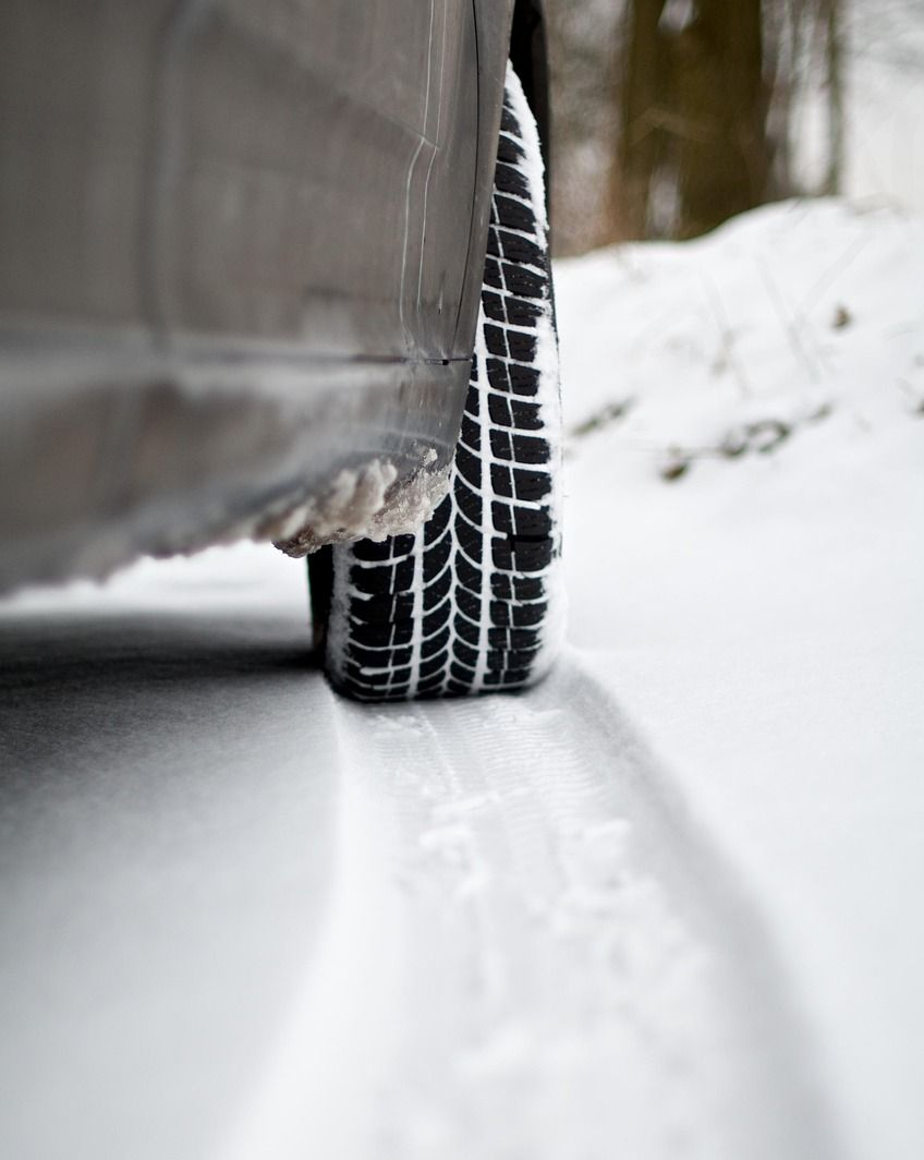 Car tire in snow, driving on a snow-covered road. Black tire with white snow on the road.