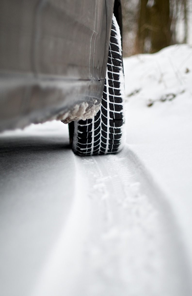Car tire in snow, driving on a snow-covered road. Black tire with white snow on the road.