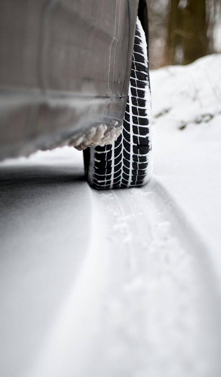 Car tire in snow, driving on a snow-covered road. Black tire with white snow on the road.