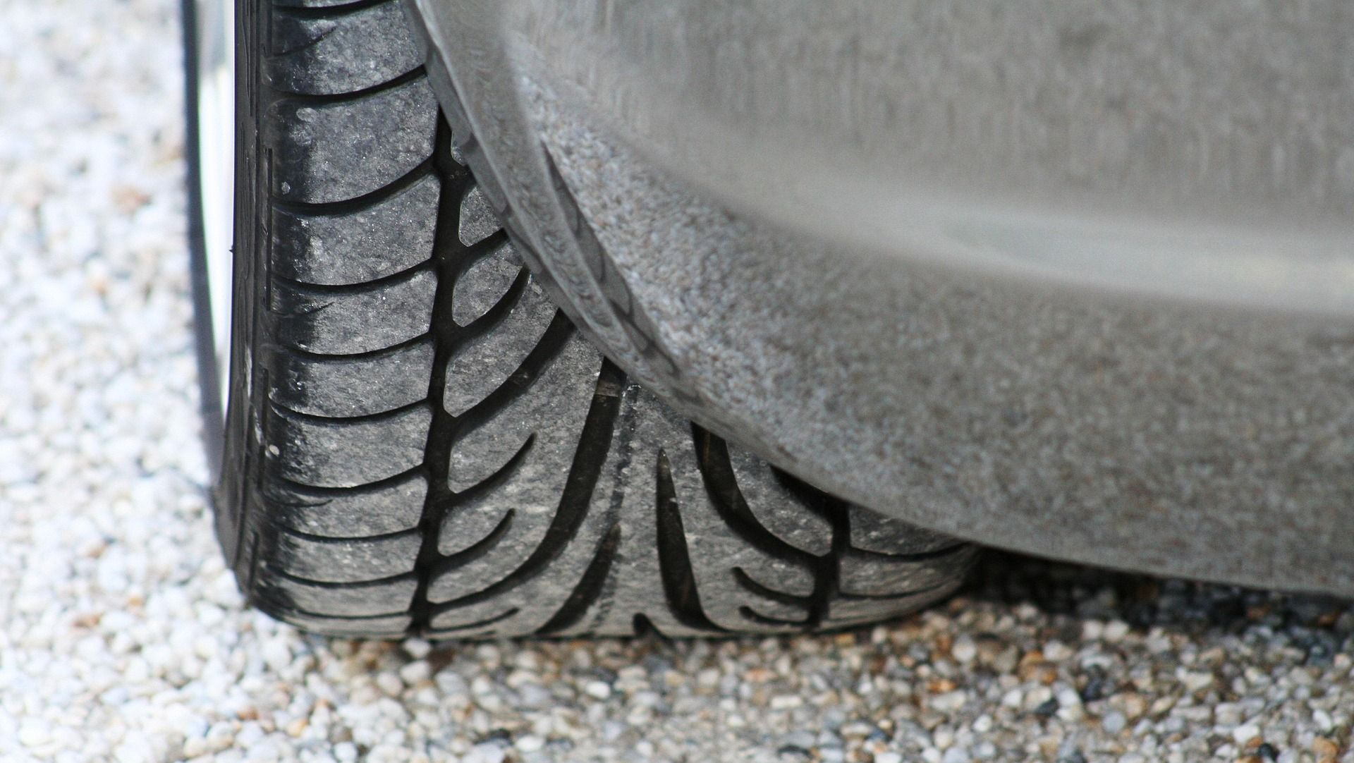 Close-up of a car tire, showing the tread pattern and its proximity to the car's body.