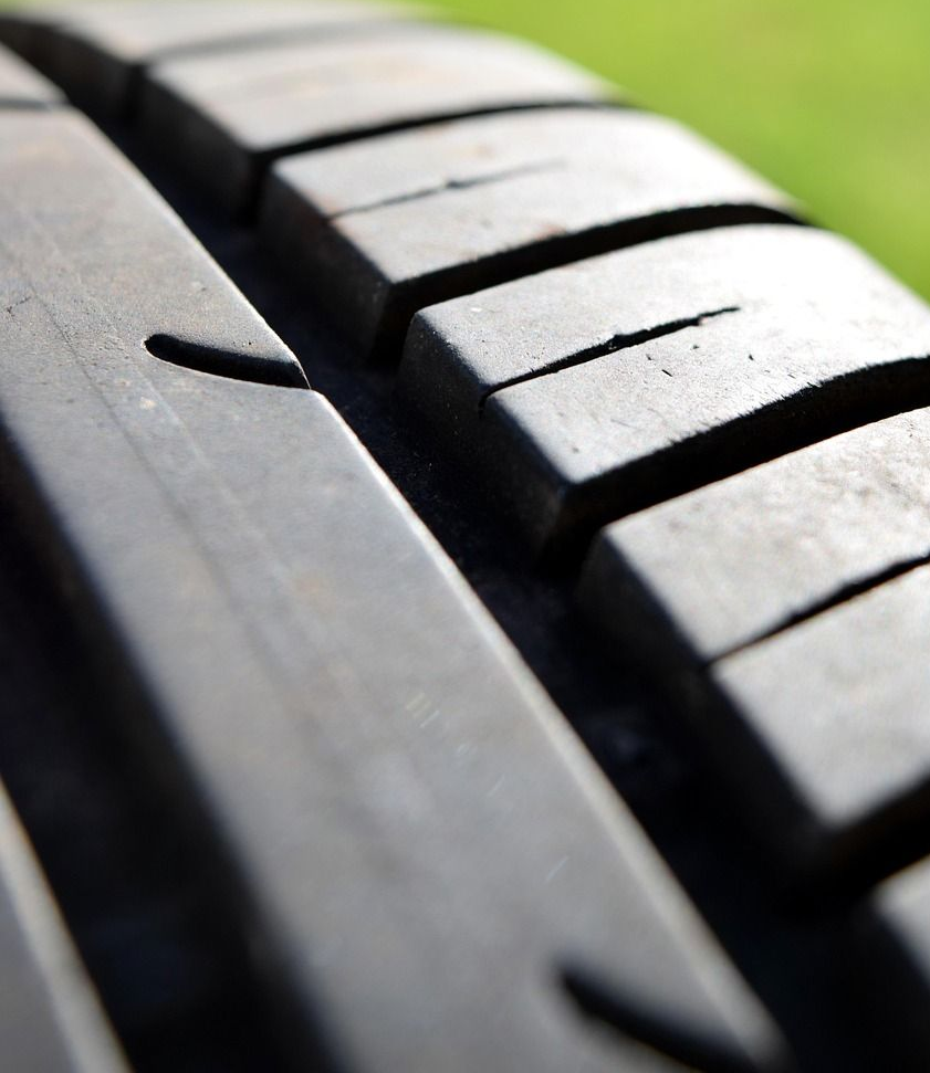 Close-up of a tire tread with grooves against a blurred green background.