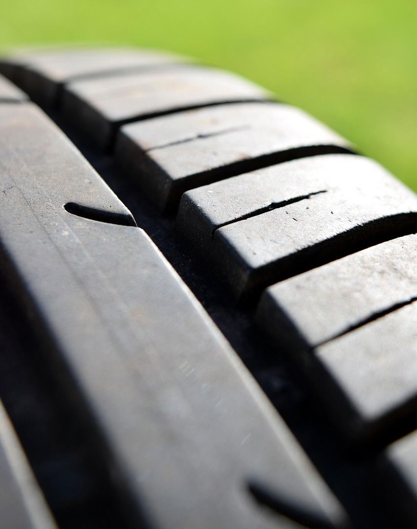 Close-up of a tire tread with grooves against a blurred green background.
