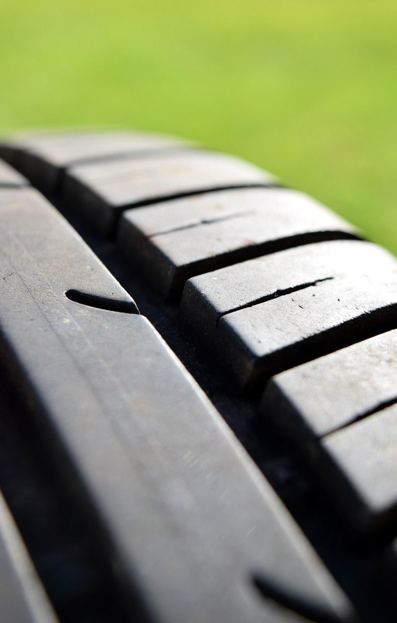 Close-up of a tire tread with grooves against a blurred green background.