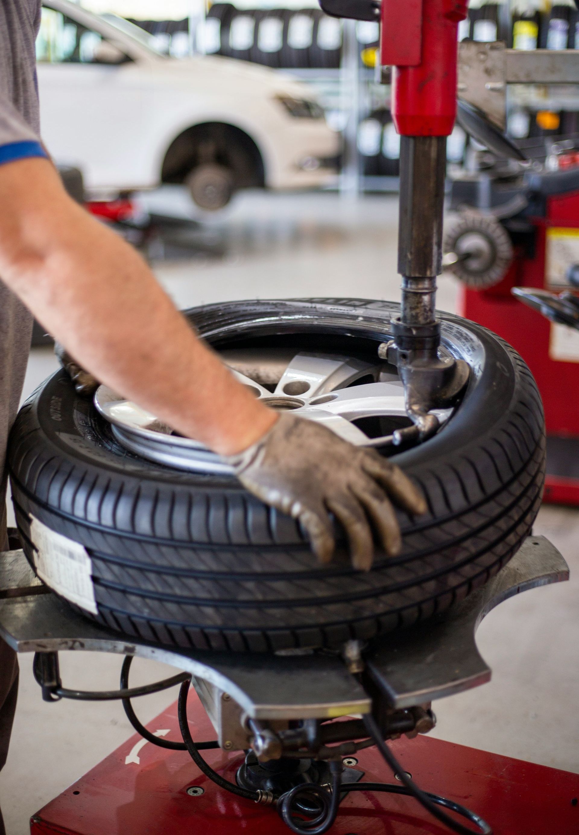 A man is changing a tire on a machine in a garage.