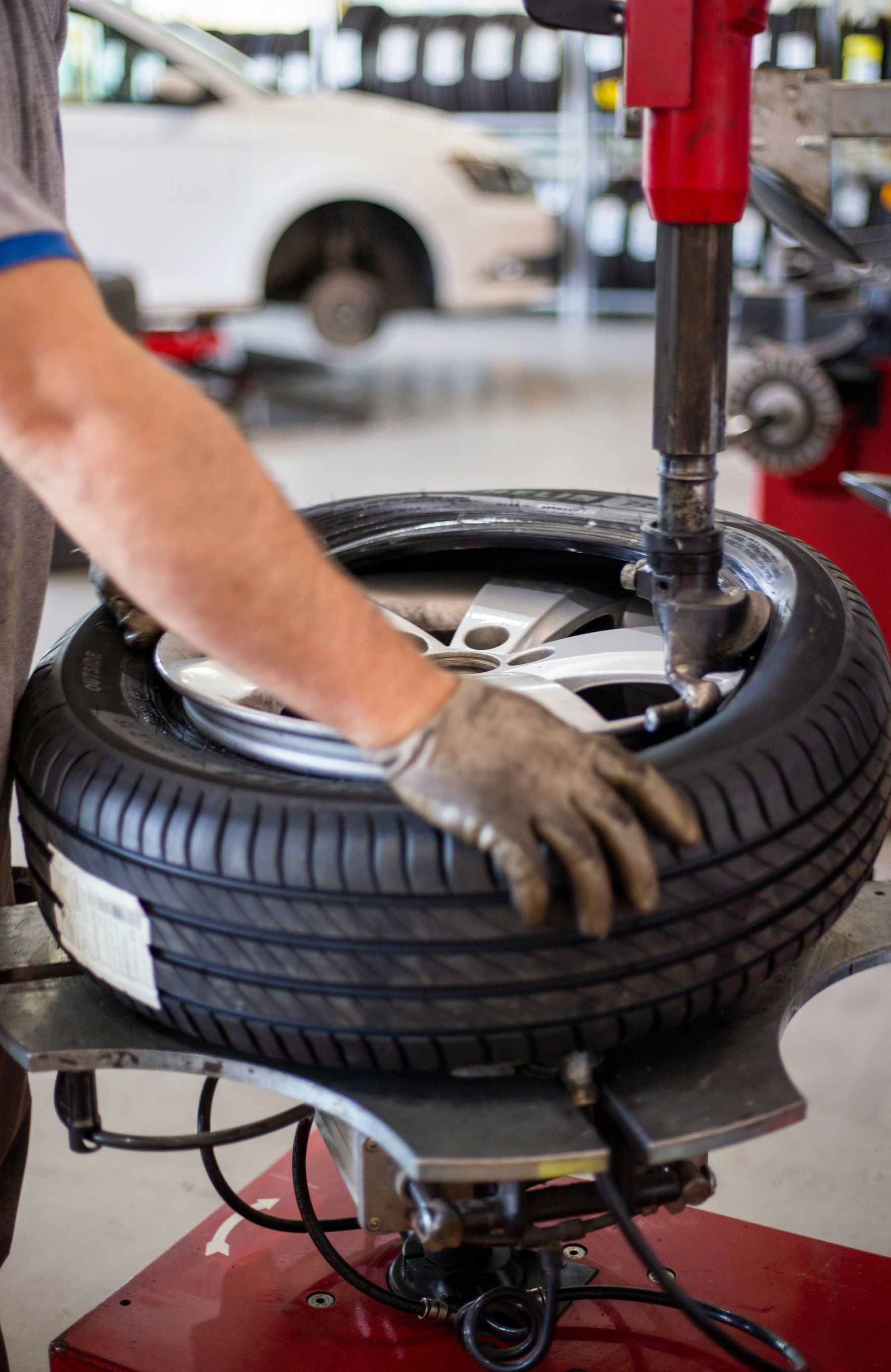 A man is changing a tire on a machine in a garage.