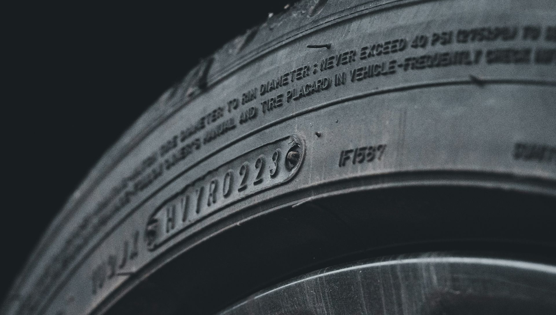 Close-up of a black tire sidewall highlighting the alphanumeric manufacturing and safety code markings.