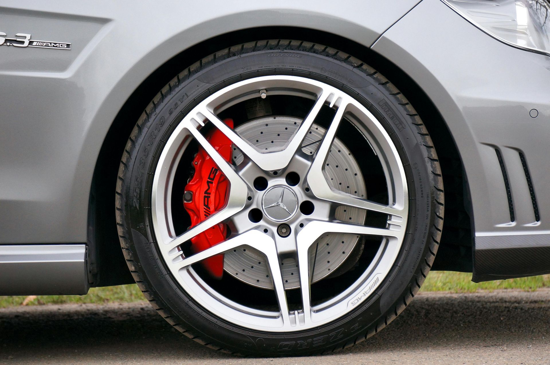 A close up of a car wheel with a red brake caliper.